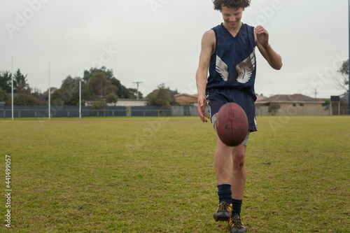 Grassroots Footy player kicking football photo