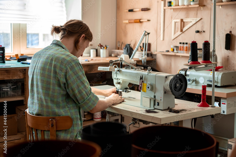 Close up craftsman hands sew stuff blank for wallet use sewing machine. Working at leather workshop Close up craftsman hands sew stuff blank for wallet use sewing machine. Working at leather workshop