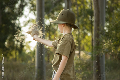 Young boy waving a bulrush seed head in the wind photo