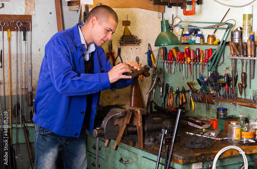 Portrait of qualified confident master of weapons working in workshop, repairing or renovating firearms . © JackF