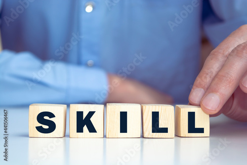 Businessman hand holding wooden cube block with SKILL business word on table background. Ability  Learn  Knowledge  Technical  Professional and Experience concepts