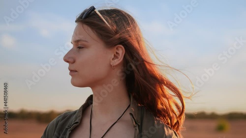 Young woman looking pleased into distance at golden hour, slow motion photo