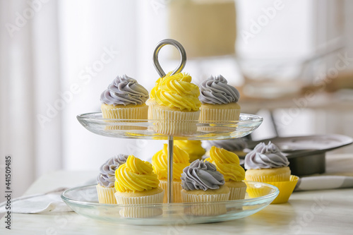 Dessert stand with tasty cupcakes on table