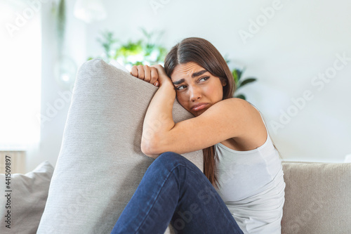 Difficult times. Portrait of a cheerless sad caucasian woman holding her hands crossed and hugging big pillow while thinking about her problems. Stock photo