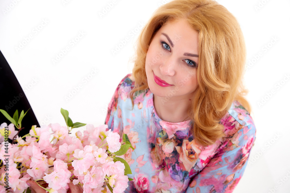 Happy beautiful woman with long blond curly hair posing with flowers in studio on white background Happy beautiful woman with long blond curly hair posing with flowers in studio on white background
