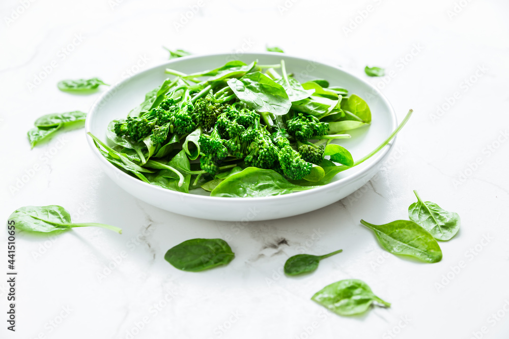 Organic spinach with broccolini (bimi) in bowl on white background Organic spinach with broccolini (bimi) in bowl on white background