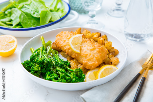 Breaded fisch fillet with spicy baked potatoes and broccoli (bimi) salad photo