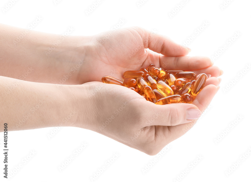 Fototapeta premium Female hands with fish oil capsules on white background