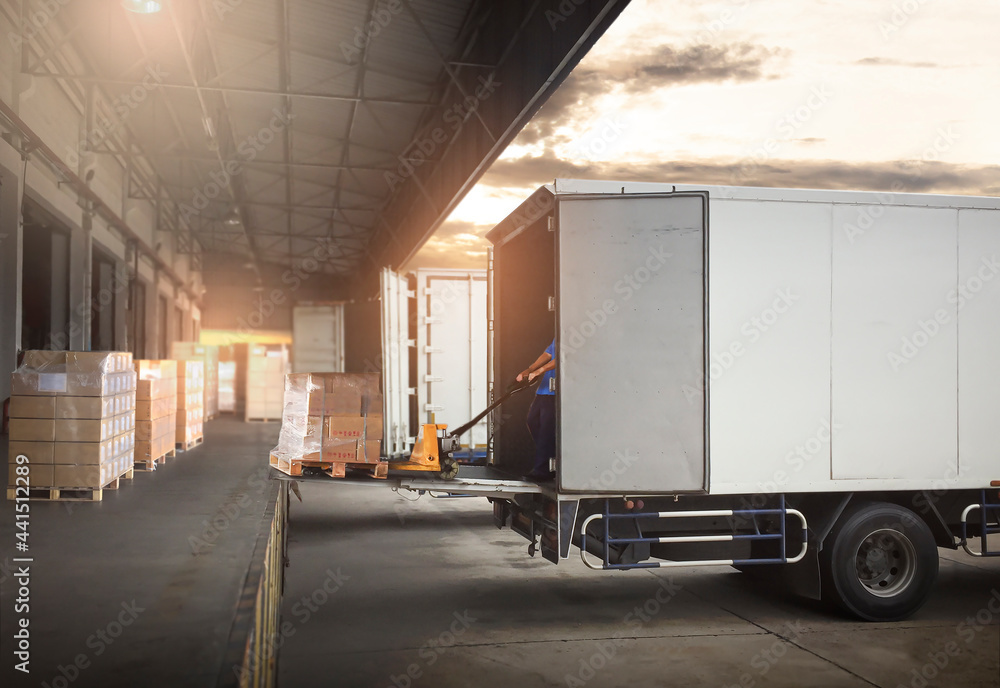 Worker Loading Package Boxes on Pallets into Cargo Container. Trucks Parked Loading at Dock Warehouse. Delivery Service. Shipping Warehouse Logistics. Road Freight Truck Transportation. Worker Loading Package Boxes on Pallets into Cargo Container. Trucks Parked Loading at Dock Warehouse. Delivery Service. Shipping Warehouse Logistics. Road Freight Truck Transportation.