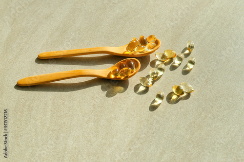 Fotografija Spoons with fish oil capsules on grey background