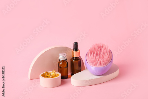 Hair brush, fish oil pills and cosmetics on color background