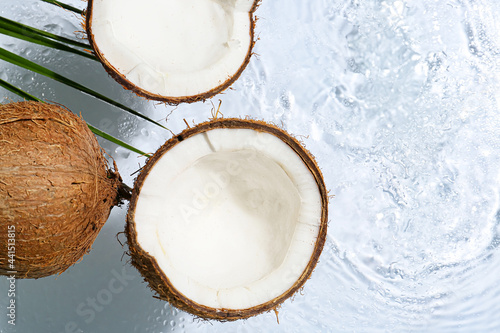 Ripe coconuts on light background with water splashes