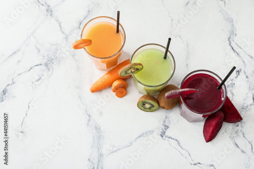 Glasses of healthy smoothie with kiwi, carrot and beetroot on light background