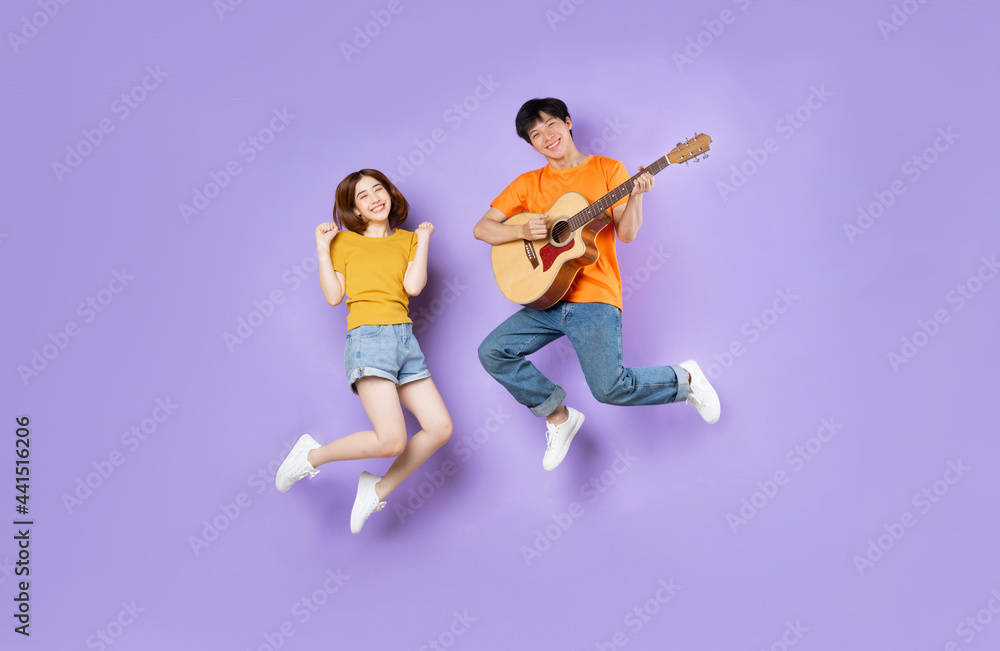 Portrait of a couple jumping up, isolated on purple background