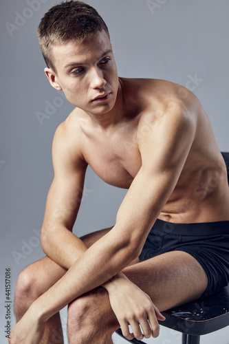 handsome man in black shorts athletic physique sitting on a chair