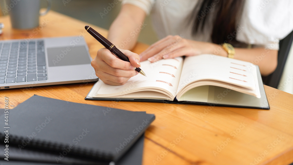 Close up view of female handwriting on schedule book in workplace Close up view of female handwriting on schedule book in workplace