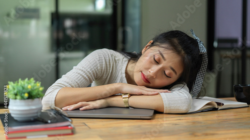 Portrait of female student take a nap while doing assignment in living room photo
