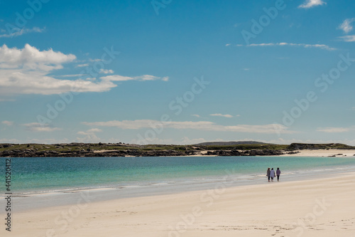 Three women enjoy Gurteen bay and beach, near Roundstone town, county Galway, Ireland, warm sunny day, cloudy sky. Beautiful Irish landscape, with clear water and light color sand © mark_gusev