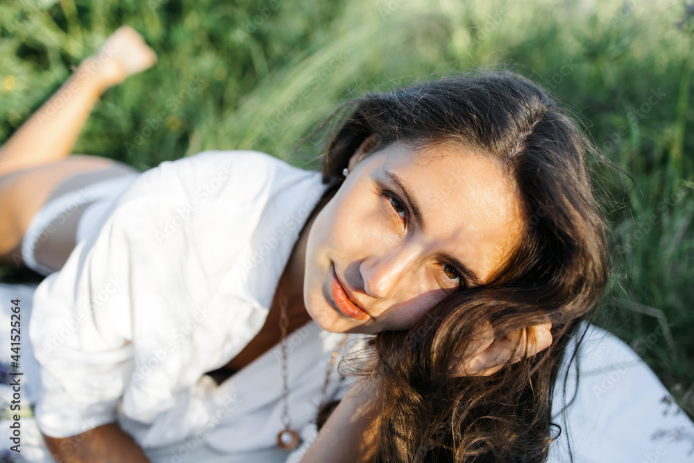 A fashionable Caucasian woman in a stylish white shirt feels free in a field with purple flowers in the sun. Lupin field in summer.The concept of a summer countryside. Close to outdoor recreation. A fashionable Caucasian woman in a stylish white shirt feels free in a field with purple flowers in the sun. Lupin field in summer.The concept of a summer countryside. Close to outdoor recreation.