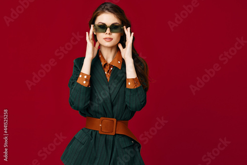 portrait of a woman wearing sunglasses suit modern style glamor model red background