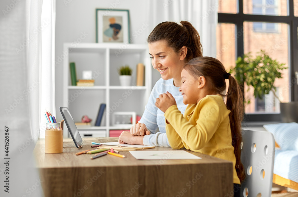 family, motherhood and leisure concept - mother spending time with her little daughter drawing with color pencils and using tablet pc computer at home