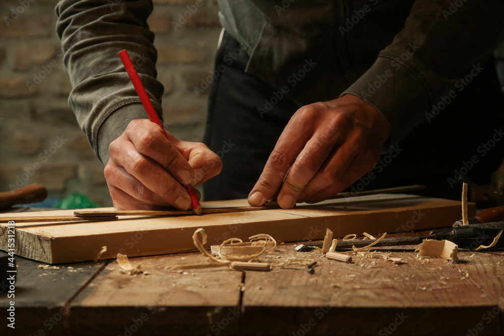 Carpenter measuring and marking wood in workshop	