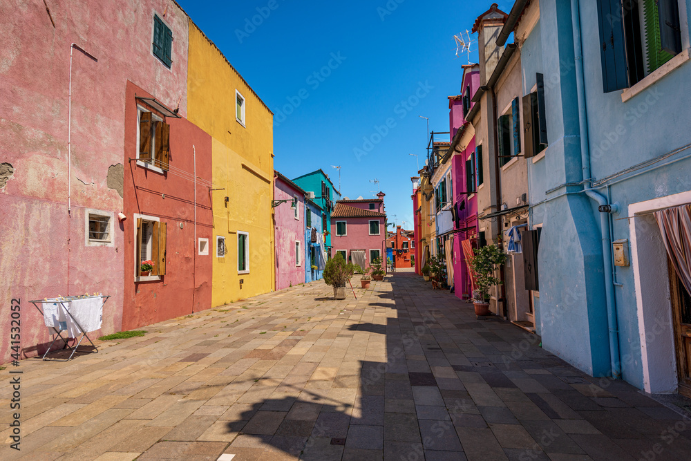 Old and small beautiful multi colored houses (bright colors) in Burano island in a sunny spring day. Venetian lagoon, Venice, UNESCO world heritage site, Veneto, Italy, southern Europe.