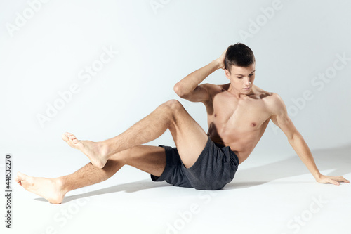 athletic guy in shorts doing exercises in a bright room bodybuilder