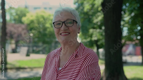 Portrait of senior woman in a park smiling to camera.