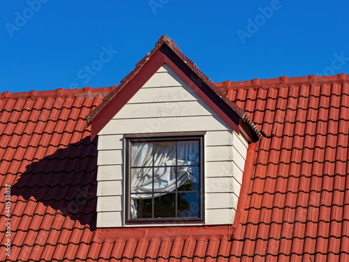 pitched roof dormer loft with white window and red concrete tiles photo