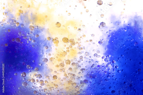 Blue and yellow paint drops in oil. Macro shot, abstract background with ink and water. Bubbles floating in space and falling. Beautiful acrylic paint. Fluid art, psychedelic gradient wallpaper.