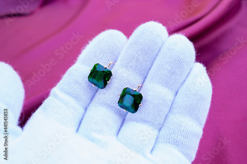 hand in white glove holds aquamarine crystal on white background