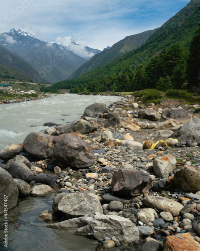 Baspa river flanked by large boulders and wooland and Himalayas with snow peaks. Chitkul, India. photo