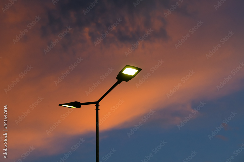 Public street lighting pole with LED lights with an amazing sunset color background. - obrazy, fototapety, plakaty 