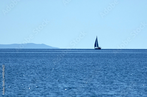 Sailing boat and blue ocean water with horizon.
