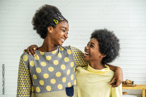 Happy Kids.Two cute adorable siblings african american children hug the neck and smile, Older sister hugs little brother by the neck photo