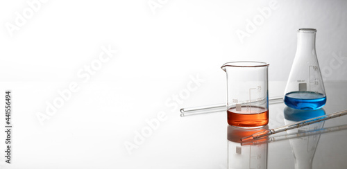 Two laboratory glass bottles and chemical liquids, pipettes on the glass table.Empty space