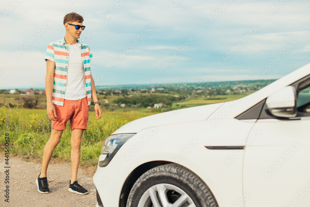 Happy young man in sunglasses, young man smiling and traveling with car outdoors