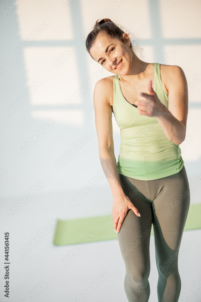 Portrait of a cheerful athletic woman in motion dressed in green sportswear during a sportbreak at fitness classroom Portrait of a cheerful athletic woman in motion dressed in green sportswear during a sportbreak at fitness classroom