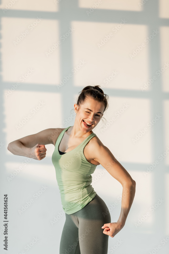 Portrait of a cheerful athletic woman in green sportswear during fitness training
