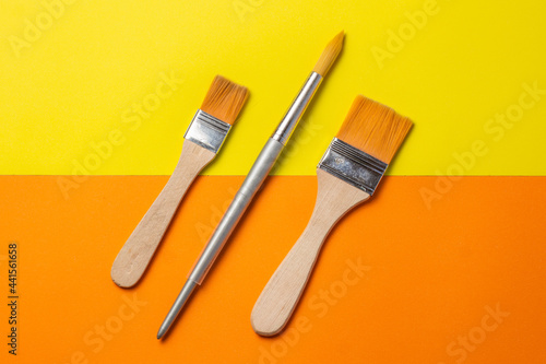 brushes and roller to paint on smooth orange and yellow background