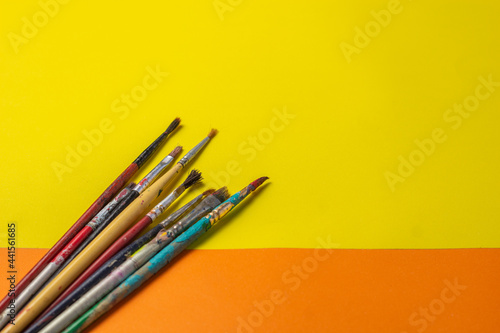 brushes and roller to paint on smooth orange and yellow background