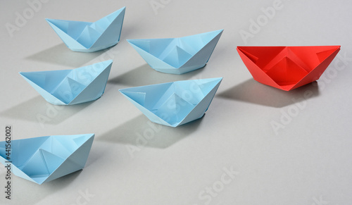 group of paper boats on a gray background. concept of a strong leader in a team, manipulation of the masses