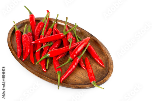 Red hot chili peppers on a wooden plate isolated on white background.