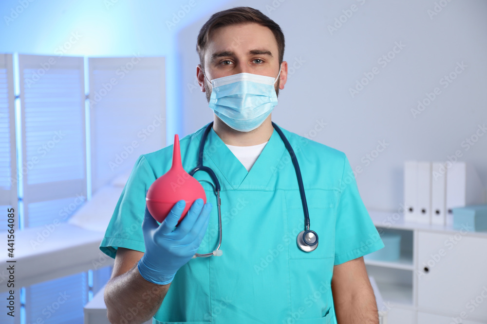 Doctor holding rubber enema in examination room Doctor holding rubber enema in examination room