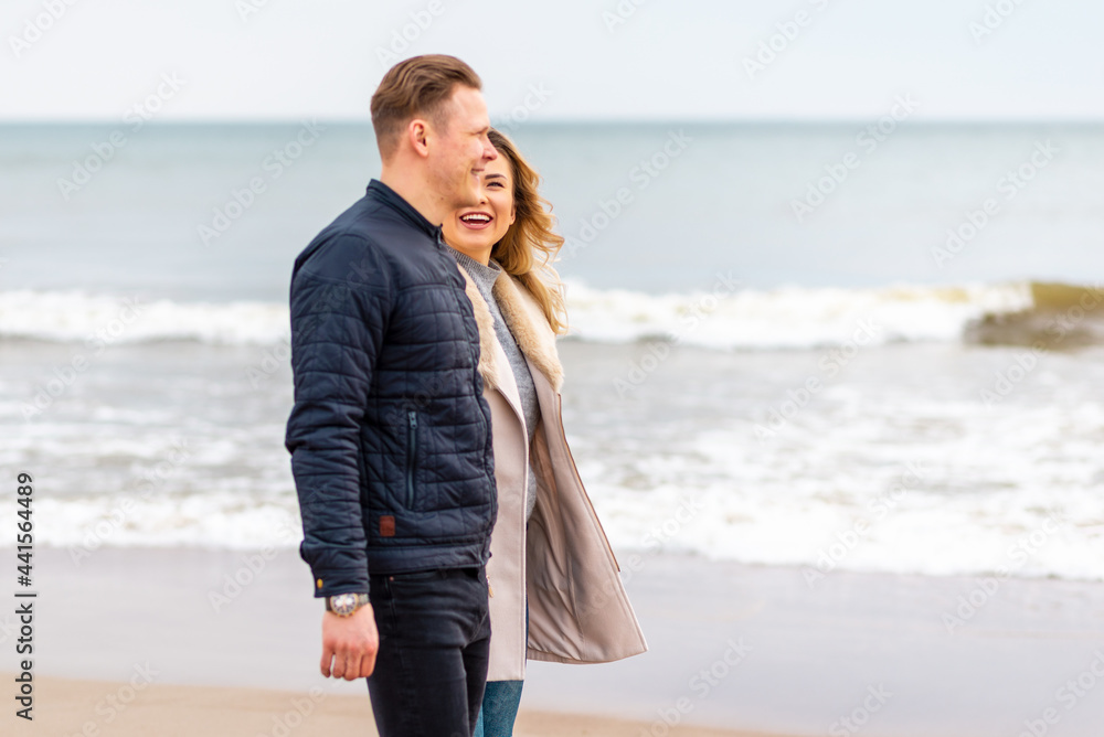 Attractive young couple walking along the shore of a sandy beach, on a spring romantic holiday, outdoors. Attractive young couple walking along the shore of a sandy beach, on a spring romantic holiday, outdoors.