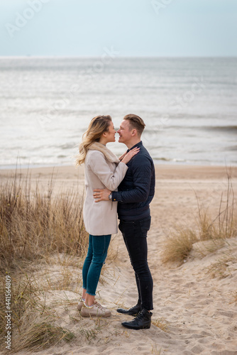 Romantic outdoor of stunning couple in love hugs and posing on the beach at evening, stylish clothes.