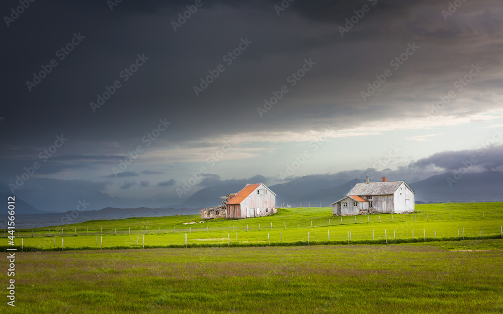 Landscape with old abandoned farm under overcast threatening sky in northern Norway