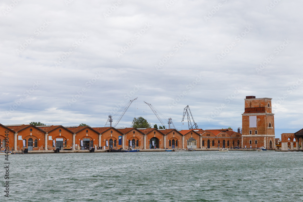 Industrial shipyards (Arsenale di Venezia) in Italy, Venice. Loading cranes and docks. Cloudy, summer.