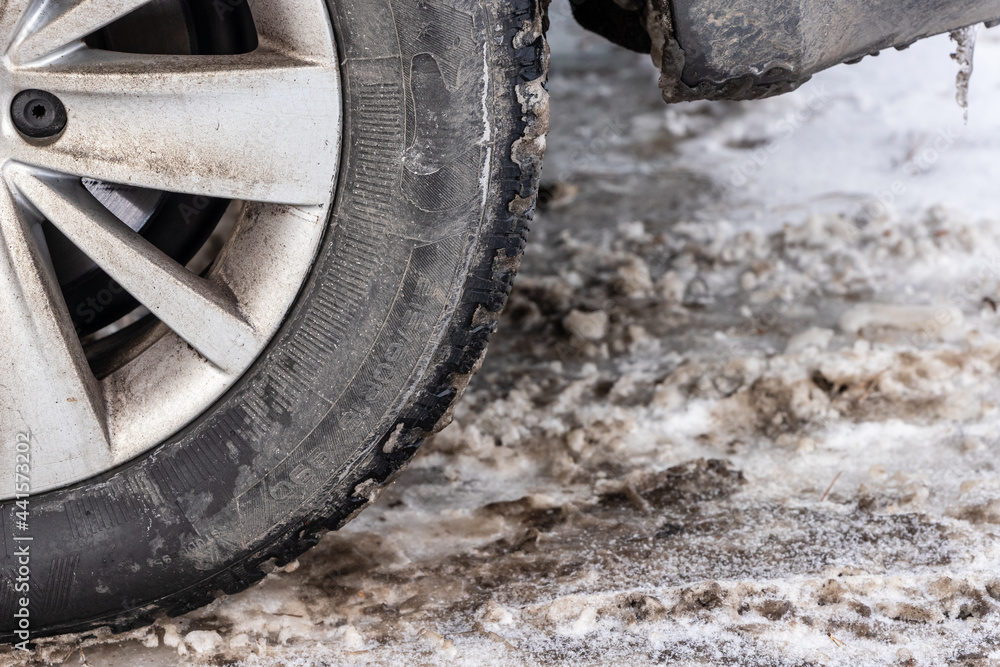 Close up photo of detail of car back wheel with dirty tire during snowy winter day. Part of car bumper, tire and wheel disk with dirt during winter Close up photo of detail of car back wheel with dirty tire during snowy winter day. Part of car bumper, tire and wheel disk with dirt during winter